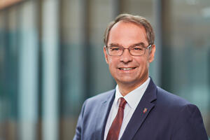 Bild vergrößern: Bürgermeister Dr. Dieter Lang im Portrait, mit blauem Anzug, weißem Hemd und roter Krawatte